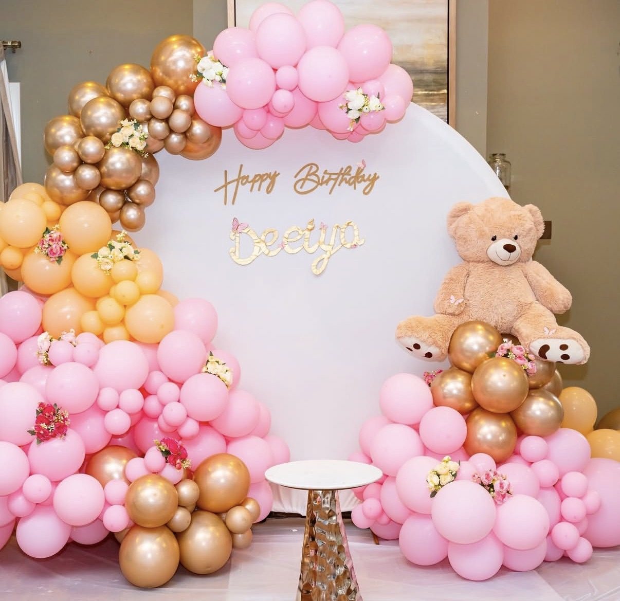 Pink-and-gold balloon backdrop at a birthday celebration