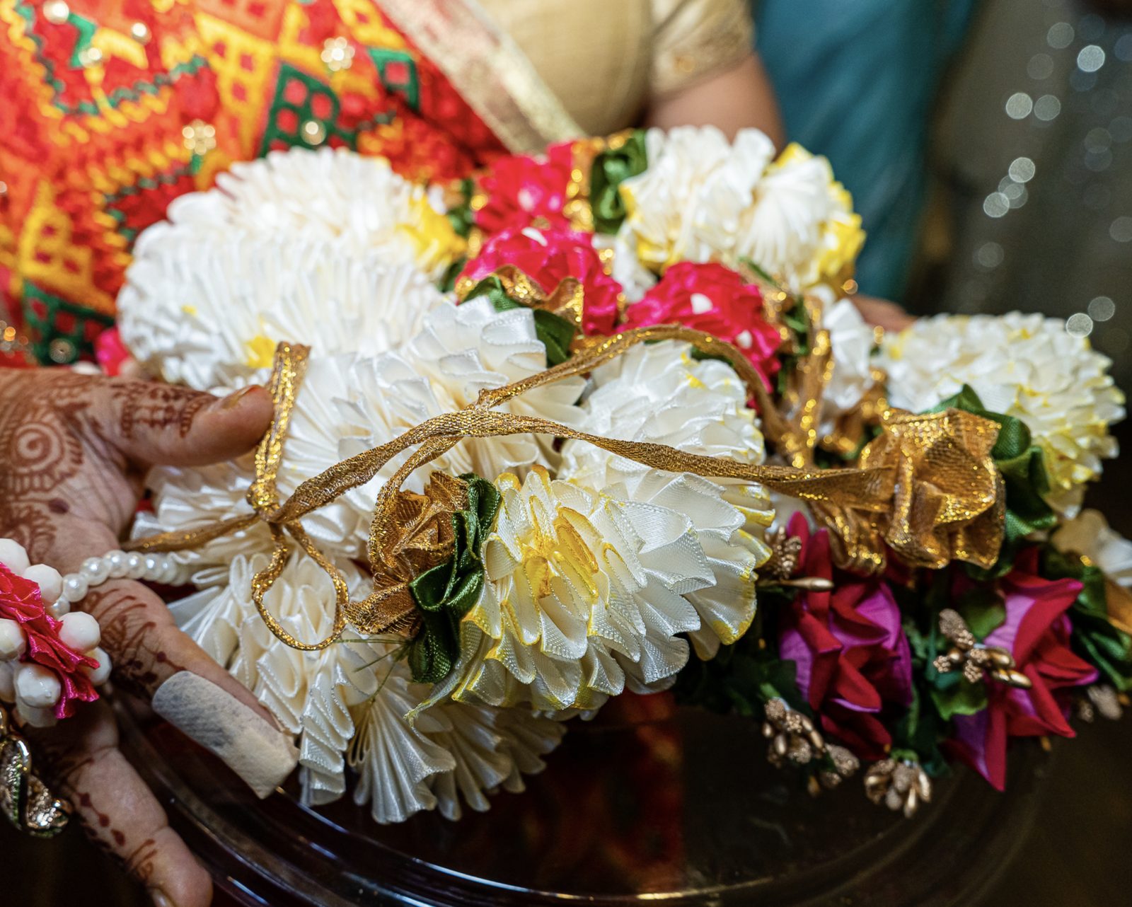 Varmala garlands held in henna-decorated hands