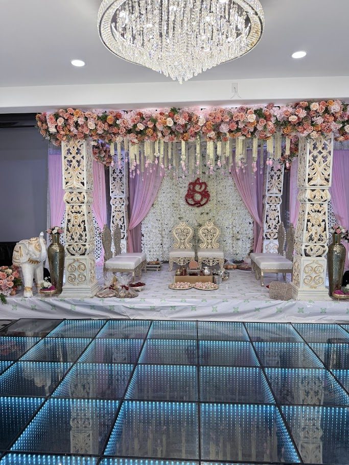Floral wedding mandap with carved pillars and a chandelier